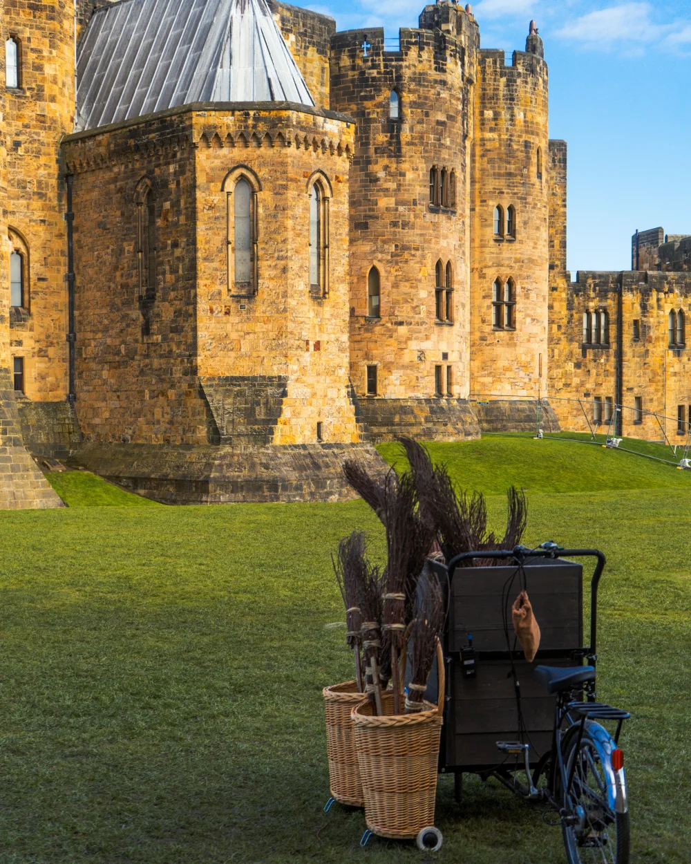 kasteel met op de voorgrond een grasveld met een bakfiets met bezemstelen