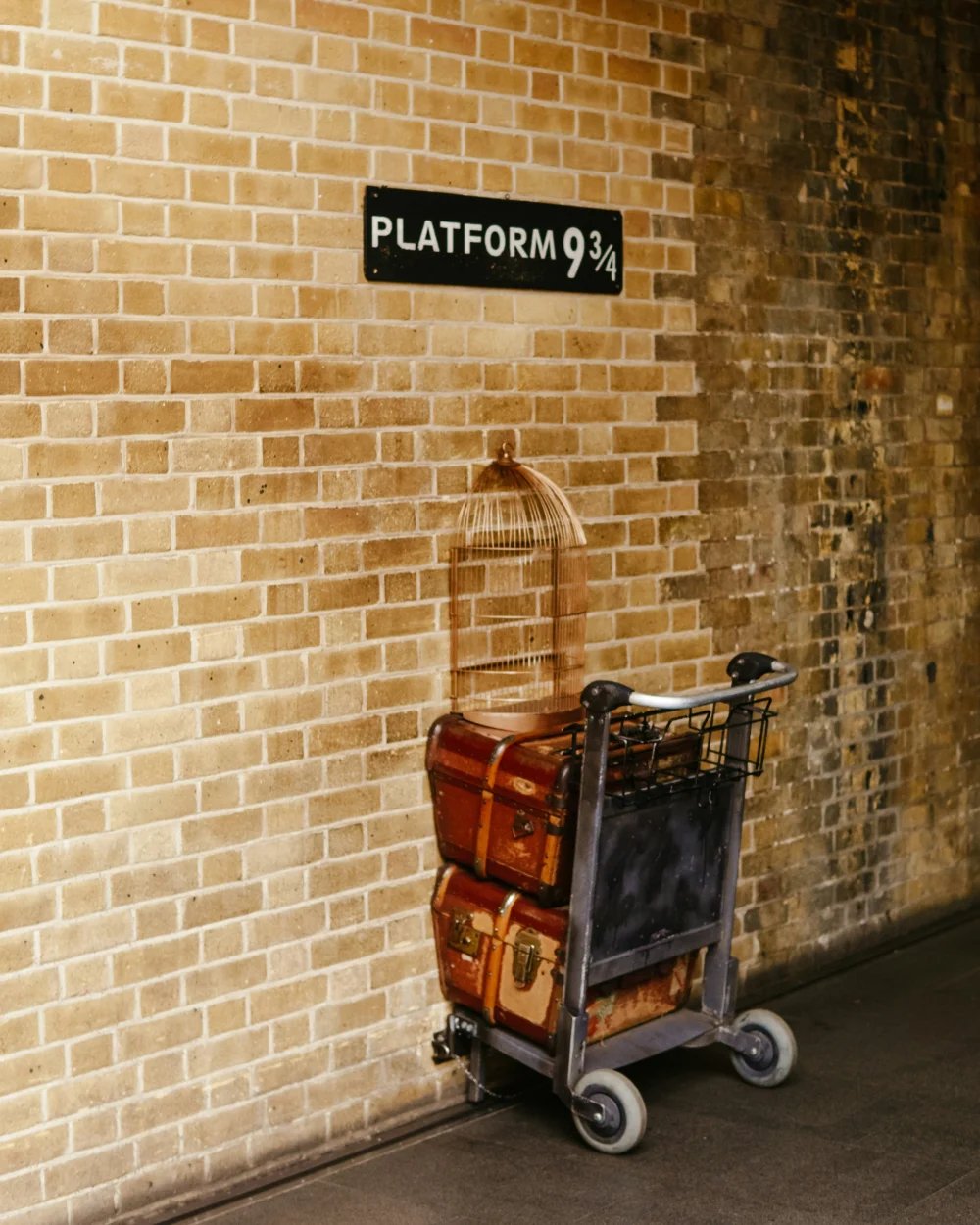 muur met bord met platform 9 3/4 met een trolley met koffers half in de muur